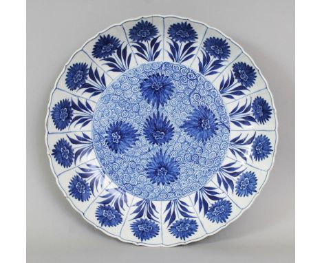 A CHINESE KANGXI PERIOD BLUE & WHITE MOULDED PORCELAIN DISH, painted to its centre with flowerheads reserved on a whorl groun