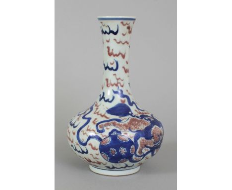 A CHINESE COPPER RED & UNDERGLAZE BLUE PORCELAIN BOTTLE VASE, decorated with two buddhistic lions playing with ribboned balls