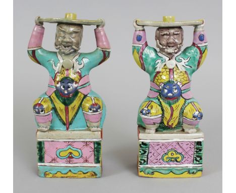 A PAIR OF CHINESE GUARDIAN FIGURE PORCELAIN JOSS STICK HOLDERS, possibly Jiaqing period, each figure squatting on a rectangul