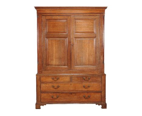 A George III oak press cupboard, circa 1770, the panel doors enclosing a hanging compartment flanked by quarter columns, the 