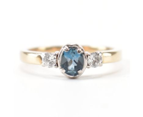 A hallmarked 9ct gold, diamond &amp; blue three stone ring. The ring having a central oval cut prong bezel set blue stone fla