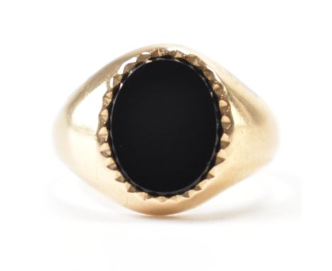 A hallmarked 9ct gold &amp; onyx signet ring. The ring having an oval onyx panel fancy bezel set to the head on a tapered sha