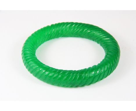 A Chinese apple green carved jade/ hardstone bangle.