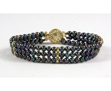 A three row black pearl bracelet on a 9ct yellow gold clasp, L. 18cm.