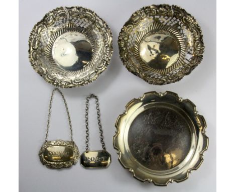 A hallmarked silver coaster, D. 12.5cms. together with two pierced silver baskets (One A/F) and two silver decanter labels.