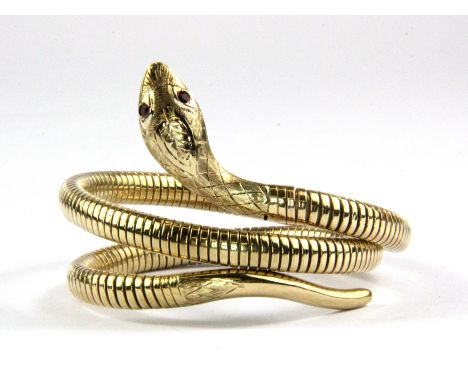A yellow metal (tested minimum 9ct yellow gold with metal core) snake shaped adjustable bangle with ruby set eyes.
