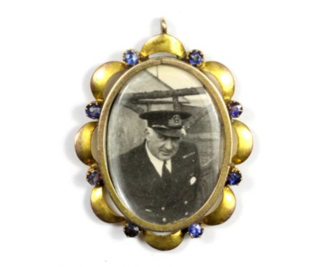 A yellow metal (tested minimum 9ct gold) double portrait pendant set with blue garnet doublets, L. 3.5cm.