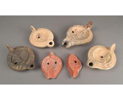 Four pottery lamps Roman and later decorated a lion and figure, a male and female bust, a figure carrying grapes and a female