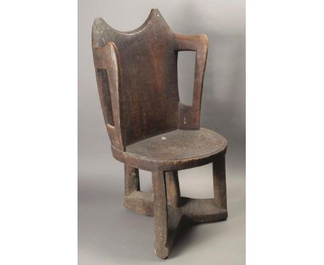 An Ethiopian armchair wood with incised linear decoration, with a shaped back and open arms with a circular seat, on four sup