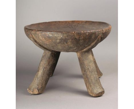 A Kenyan stool wood, with a circular dished top on four legs with pointed moulded tops, 23cm high, 32cm diameter. Provenance 