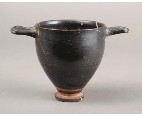 A black glazed skyphos Greek raised on a circular foot with incised line decoration and a pair of open handles, 9cm high.