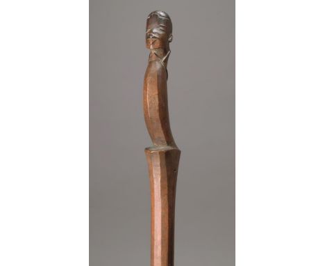 A Makonde stirring implement Mozambique wood, with a carved head finial and a curved faceted torso to a spatulate terminal, 9