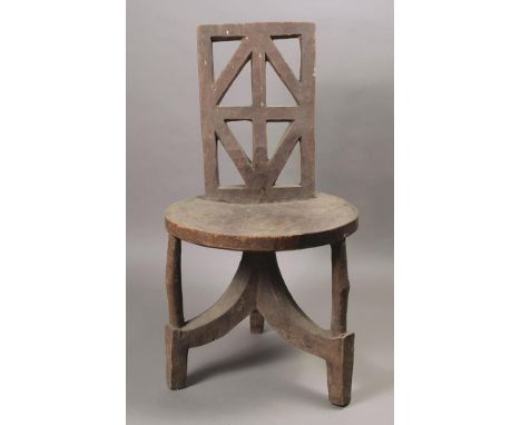 An Ethiopian chair wood with a pierced lattice panel back, with a circular seat and tripod base, 87cm high, 47cm wide.