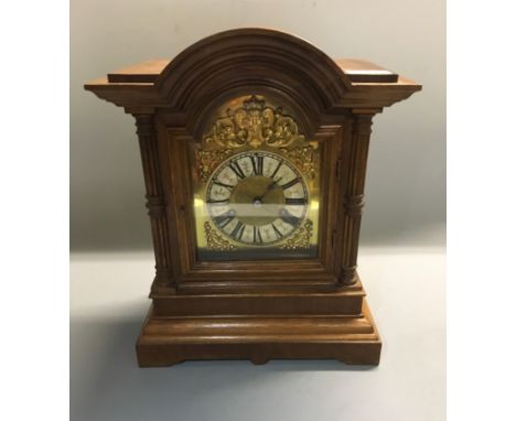 An oak case mantel clock with brass detail to face.