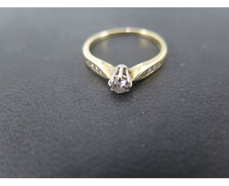 A ladies 18ct yellow gold diamond solitaire ring - the brilliant cut stone measures approx 0.18ct - a further 8 small diamond