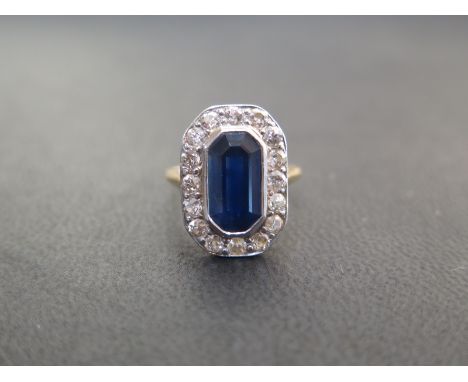 A foreign 20th century  yellow and rose gold cluster ring comprising one oblong cut corner step cut blue sapphire secured in 