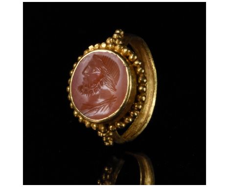 c. 1-300 AD. Roman. A heavy gold ring with a D-shaped hoop and a circular bezel framed with applied granulations and enclosin