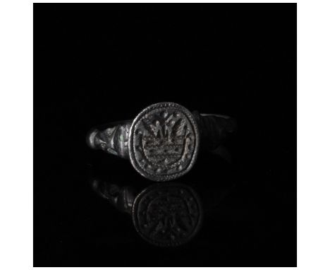 C. 1100, Viking Age. A heavy silver ring is comprised of a circular hoop with flaring shoulders and a round bezel bearing inc