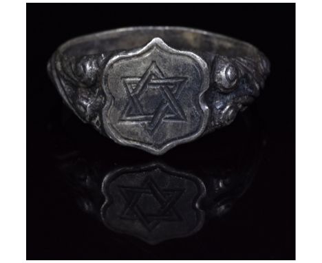 c. 1200 - 1500 AD, Medieval. Silver ring with D-shaped hoop with ornate draped decoration and flattened, polygonal bezel feat