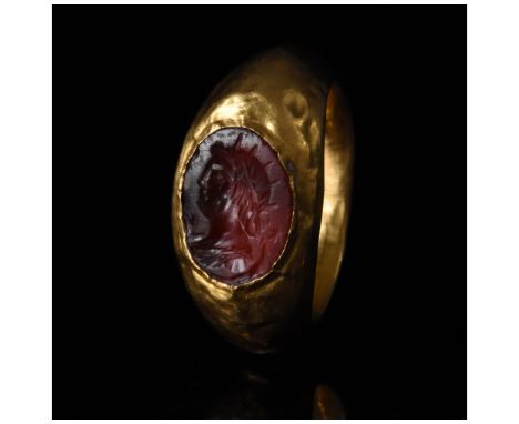 1-300 AD, Roman. Gold ring with D-shaped hoop, and an elliptical bezel with a red gem intaglio bearing a bust of Sol Invictus