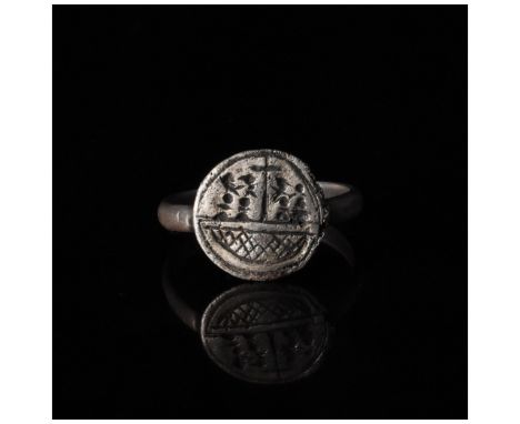 c. 1000-1500 AD. Medieval. A silver ring with a round hoop and a circular bezel bearing incised decoration in the form of a s