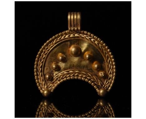 Ca. 100 AD, Roman. Gold lunar amulet comprises a crescent moon with suspension loop, corded border and applied spheres. In Ro