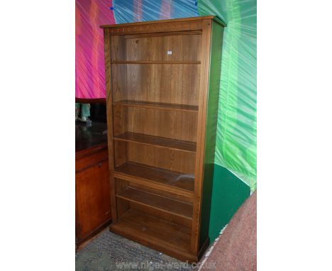 An Ercol style open Bookcase with plain top over carved frieze having one fixed and four adjustable shelves, on plinth base, 