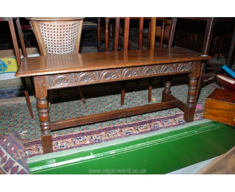 A reproduction Oak Priory style Bench Stool with bull nose moulded edge, one piece top on carved frieze with gently splayed t