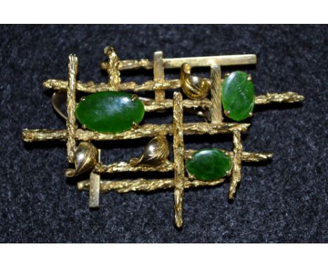 A modernist jade and yellow metal multi layer lattice pendant brooch, inset with three oval jade panels, leaf and branch body