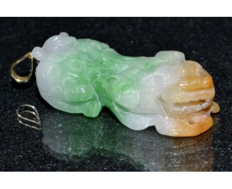 A Chinese banded jade temple lion pendant , amber head, green and white banded body and tail, yellow metal loop and ring susp