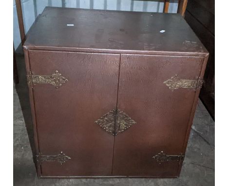 A vintage Korean brown leather two door table top cabinet having cast metal supports and glass shelf, 61.5h x 61wLocation: RC
