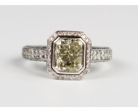 A Hans D. Krieger Radiant Cut Diamond Ring in a rub over setting surrounded by brilliant cut stones and further to the closed