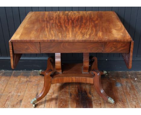 An Early 19th Century Mahogany Drop Leaf Sofa Table raised on twin lyre shaped supports with quadruped swept legs and brass c