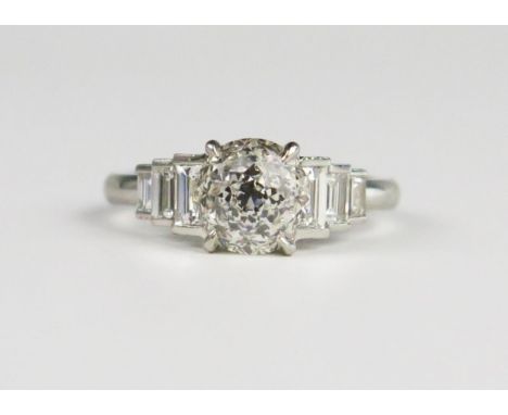 A Hans D. Krieger Diamond Ring in a .950 Platinum Setting, the central round novelty cut stone flanked by three graduate bagu