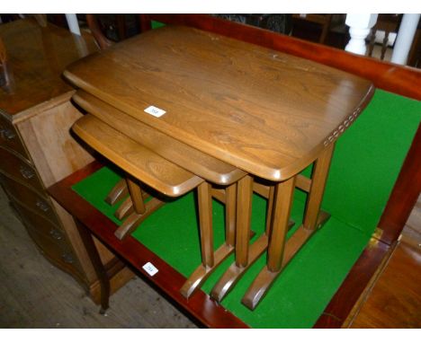 An Ercol medium elm nest of three graduated coffee tables, raised on octagonal uprights  