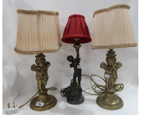 A pair of cherub table lamps and another single lamp Condition Report: The gilded lamps have some rubbing to them. The spelte