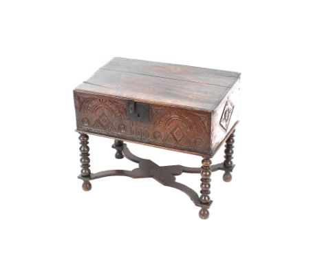 An Antique oak Bible box on stand, the hinged lid above a square iron lock-plate and carved frieze, dated 1643, raised on bob