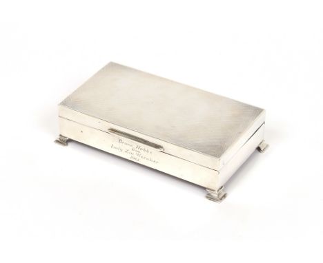 A silver engine turned decorated cigarette box, wood lined interior, presentation inscription, raised on stepped feet, Birmin