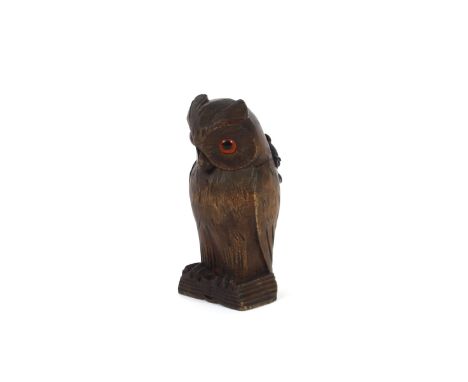 A 20th Century Black Forest type pin cushion, in the form of an eagle owl with glass eyes, circular pad for pins, standing on