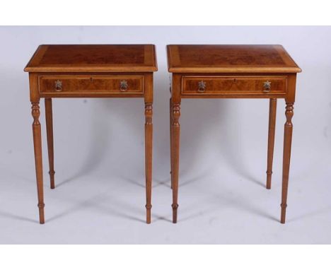 A pair of figured walnut lamp tables, each having a cross and feather banded top over single frieze drawer, raised on ring tu