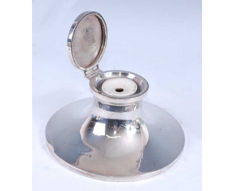 A George V silver capstan inkwell, of flaring circular form with hinged cover and removable ceramic glass inset, on a wooden 