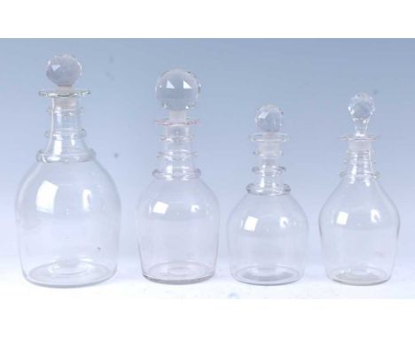 * A graduated set of late Georgian lead glass decanters, the facet cut ball stoppers above a triple ring neck and mallet form