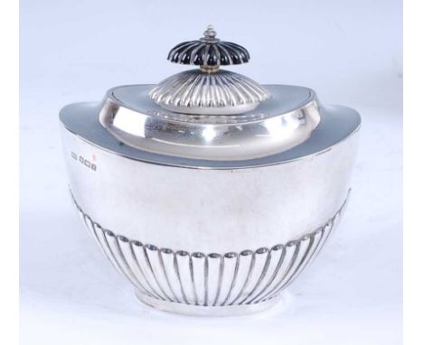 A George V silver tea caddy, of half-gadrooned tapering oval form, having a hinged domed gadrooned cover with ebonised finial