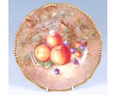 A Royal Worcester porcelain cabinet plate, painted with fruit on a mossy bank by J Cook, signed, within a gilded gadrooned bo