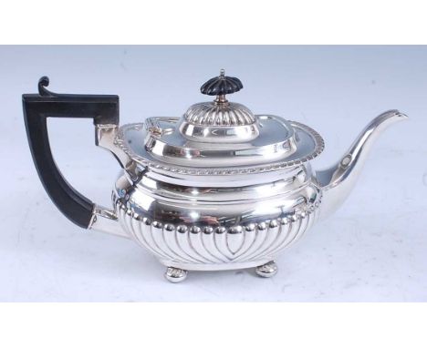 A George V silver teapot, of half-reeded oval bombe form, having angular C-scroll wooden handle, the hinged domed and reeded 