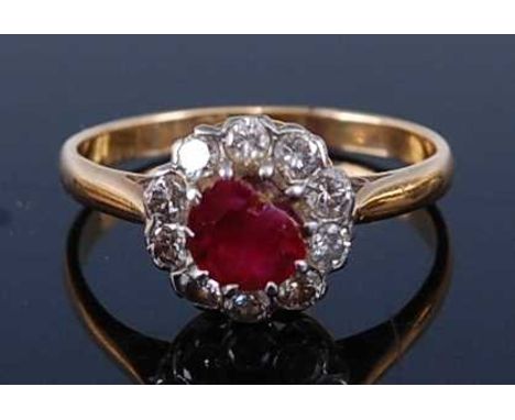 An 18ct gold and platinum, ruby and diamond flower head cluster ring, the round cut ruby (badly chipped) weighing approx 0.4 