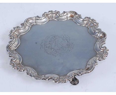 A mid-18th century Irish silver card waiter, having a raised piecrust rim, engraved armorial, and on stepped hoof feet, 7.5oz