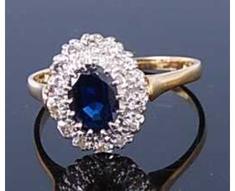 A yellow and white metal, sapphire and diamond oval cluster ring, comprising an oval faceted sapphire within a border of four