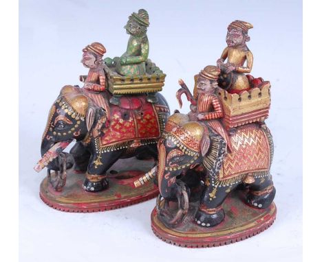 * A pair of 19th century Indian carved and stained ivory figures, each in the form of a caparisoned elephant with houdah carr