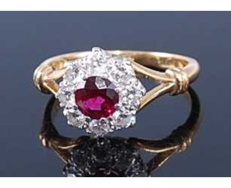 An 18ct gold, ruby and diamond flower head cluster ring, the centre round cut ruby weighing approx 0.65 carats, within a surr